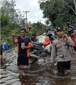 Jalan Lundang Baru Terendam Banjir, Bhabin Polsek Dedai Bantu Warga Pikul Motor